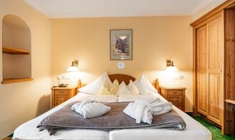 A cozy bedroom with a large bed and soft pillows.  
Warm wooden furniture and gentle lighting create a relaxed atmosphere.