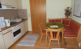 A cozy kitchen with a dining table and chairs. The walls are light, and there is a beautiful rug on the floor.