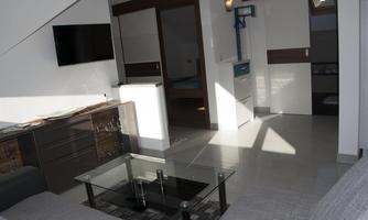 A modern apartment with a cozy living room and a large window. The space is bright and welcoming.
