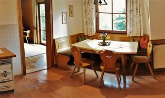 A modern kitchen with wooden details and a cozy dining area. Plenty of daylight creates an inviting atmosphere.