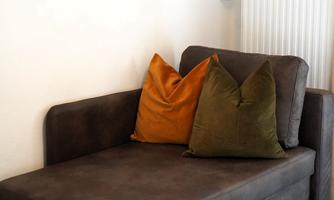 A cozy armchair with two cushions in warm colors. In the background, a radiator is visible.