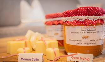 A beautiful arrangement with jars of honey and handmade soap on a wooden table. The jars are decorated with colorful fabrics and labels.