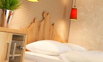 A modern bedroom with a wooden bed and red lamps. On the nightstand, there is a small plant.