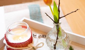 A decorative tray with a candle, a tulip, and two wooden hearts. The green moss base provides a cozy atmosphere.