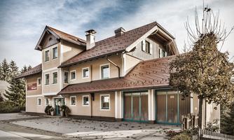 A beautiful two-story building with a traditional roof. The facade is bright, surrounded by trees and a quiet environment.
