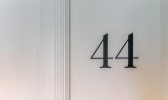 A simple wall with the number 44 in large, black digits. The background is light and neutral.