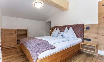 A cozy bedroom with a double bed and wooden paneling. The atmosphere is modern and inviting.