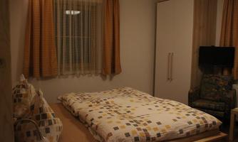 A cozy bedroom with a large bed and colorful pillows. There is a window with curtains and a television in the room.