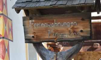 A wooden sign with the inscription "Ferienwohnungen Fingerlos". The lettering is styled in a traditional font.