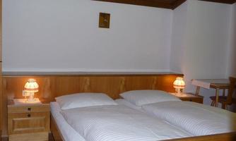 A cozy bedroom with a double bed and two bedside lamps. The walls are in a simple, light color.