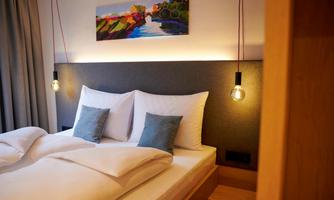 A modern bedroom with a large bed and cozy pillows. On the wall hangs a piece of art depicting a landscape.