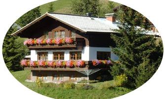 A traditional old building with flower boxes and a beautiful garden. Surrounded by green meadows and trees.