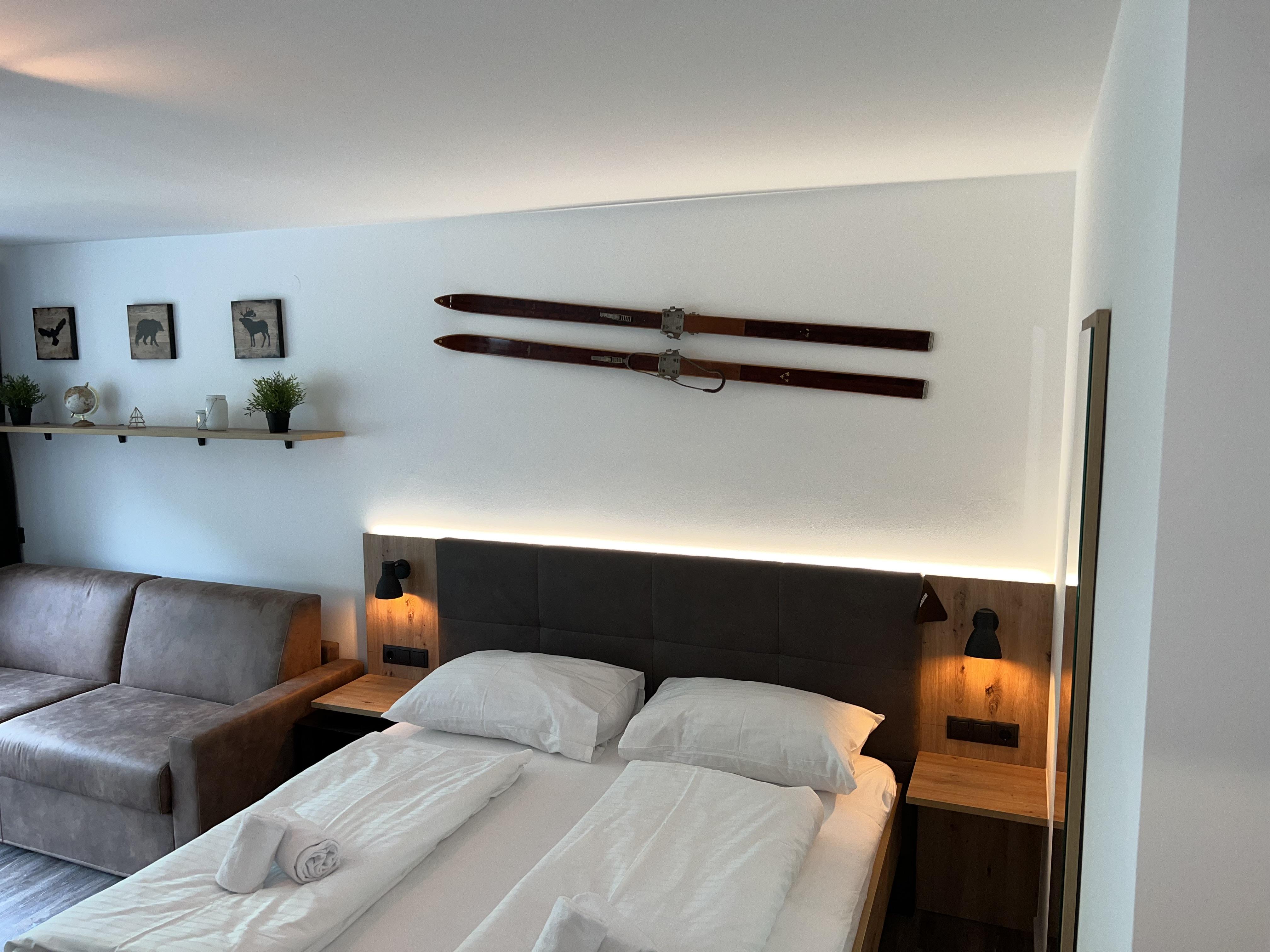 A modern bedroom with a double bed and cozy furnishings. Old skis hang on the wall, enhancing the alpine atmosphere.