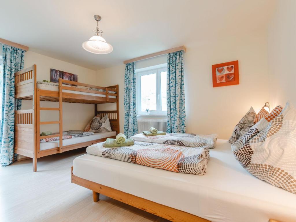 <p>Bright, friendly furnished bedroom with a double bed and a wooden bunk bed. The beds are dressed in colorful bedding, blue patterned curtains hang at the windows and a ceiling light provides pleasant illumination.</p>