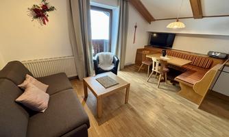 A cozy living space with a sofa, a table, and a television. There is a lot of wood and natural light sources that create an inviting atmosphere.