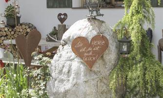 A large stone in the garden with a heart-shaped wooden sign. It says: "Where the heart is, there is happiness!"