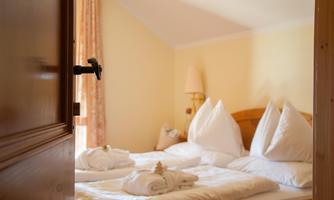 A cozy bedroom with a double bed and freshly made bedding.  

Soft towels are ready, and the light gently shines through the window.