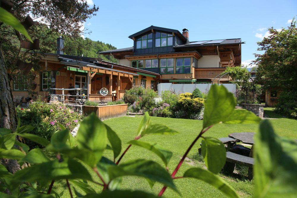 A charming wooden house surrounded by a well-maintained garden. Colorful flowers and a green lawn create an inviting atmosphere.