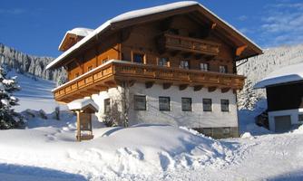 A beautiful wooden house in winter, surrounded by a lot of snow. The clear blue sky complements the winter landscape.