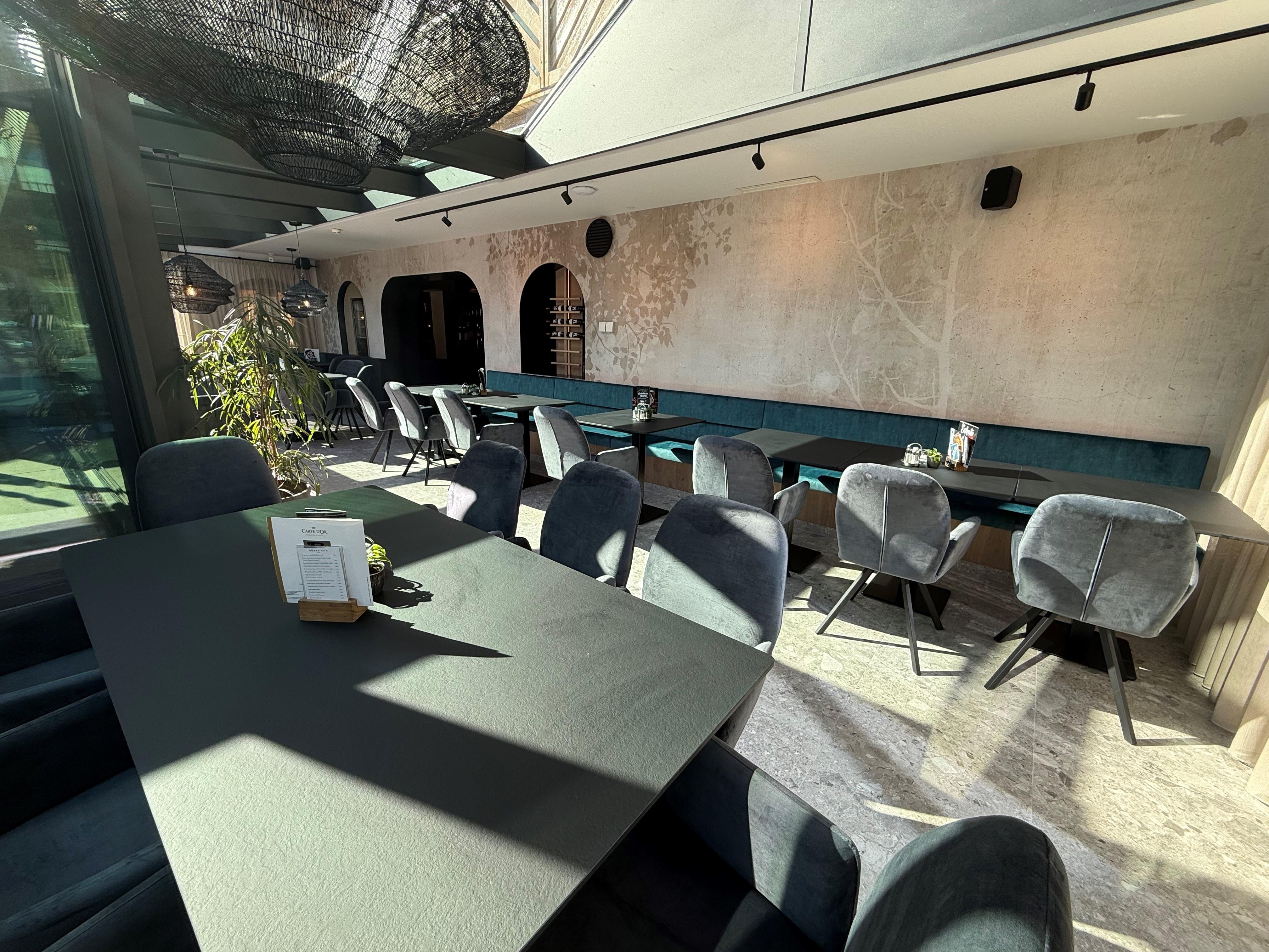 A modern conservatory with stylish seating and a bright, inviting atmosphere. Large windows let in plenty of daylight.