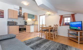 A cozy living kitchen with modern amenities and a dining area. The space is bright and inviting, perfect for relaxed stays.