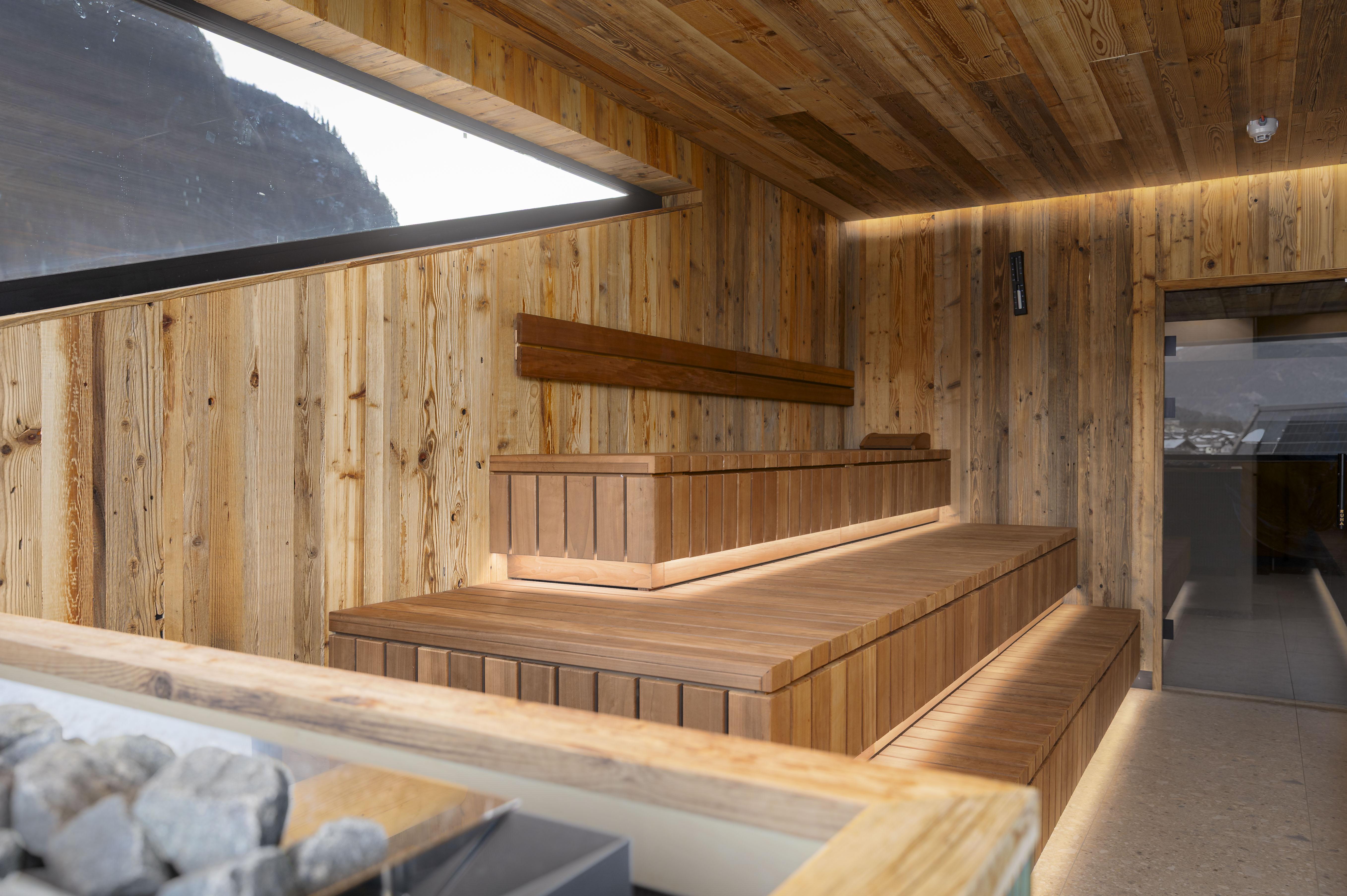 A modern sauna interior with wood paneling and soft lighting. The benches provide cozy space for relaxation.