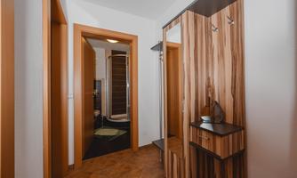 A modern hallway with a mirror and a narrow shelf. In the background, a door to a bathroom is visible.