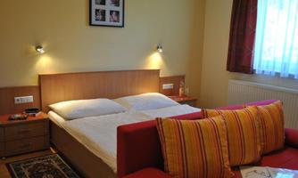 A cozy bedroom with a double bed and a red sofa. Soft lighting and a window create an inviting atmosphere.