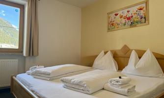 A cozy room with a double bed and fresh bedding. A window lets in light and offers a view of the surrounding nature.