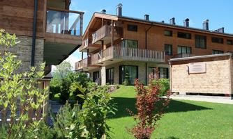 Modern residential buildings with balconies in a clean environment. Green lawns and plants surround the houses.