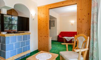 A cozy living room with a red sofa and a television. The room has a rustic style and plenty of daylight.