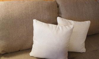 A cozy sofa with brown fabric and two decorative cushions. The cushions have a classic pattern and complement the decor.