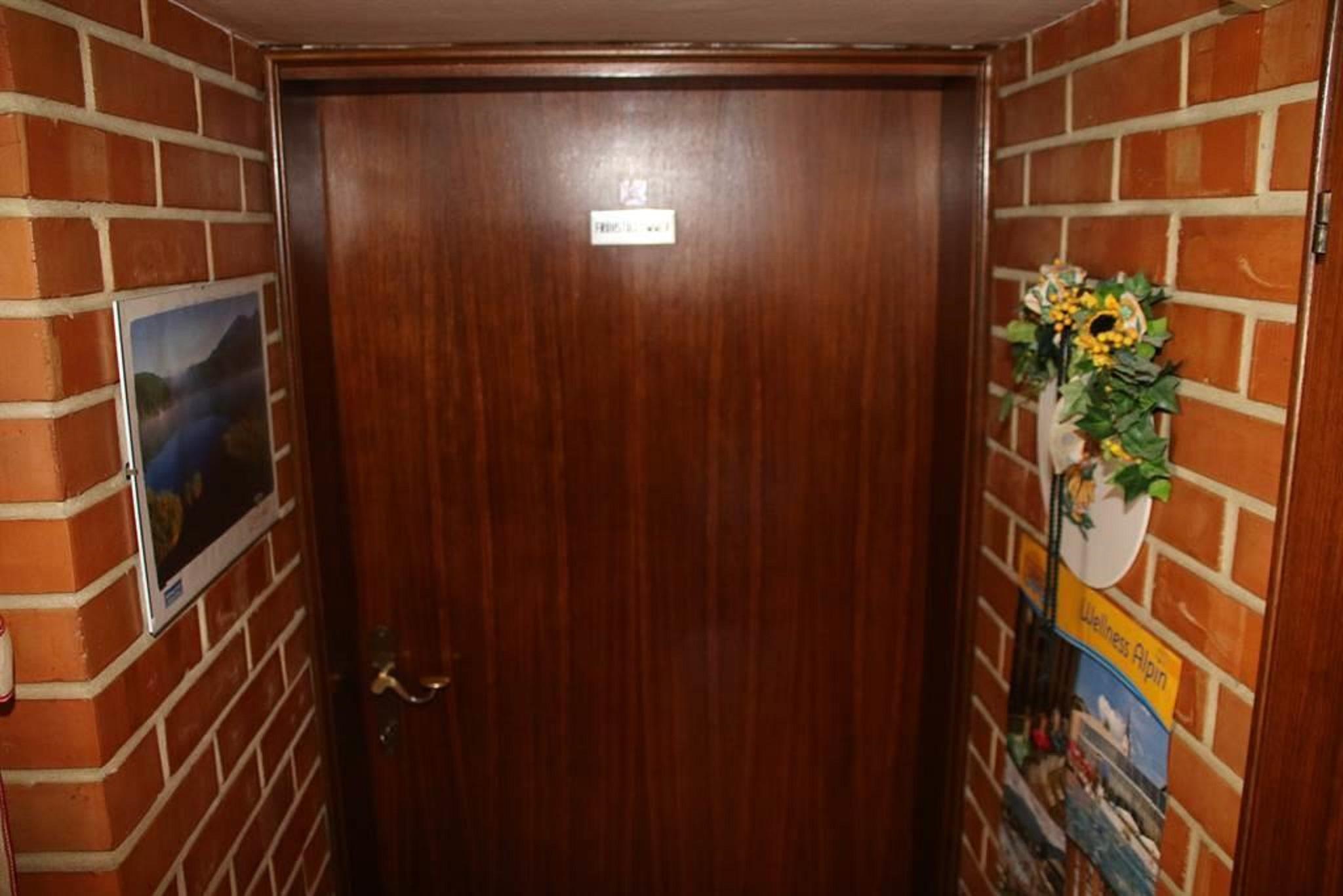 A wooden-look door in a brick wall area. Pictures and decorations are mounted on the wall.