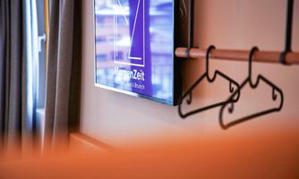 A modern room with a television on the wall and a clothes rack. The atmosphere is cozy and inviting.