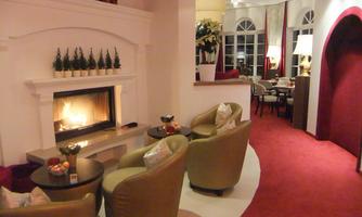 An elegant living space with comfortable armchairs and an open fireplace. The warm colors and soft lighting create an inviting atmosphere.