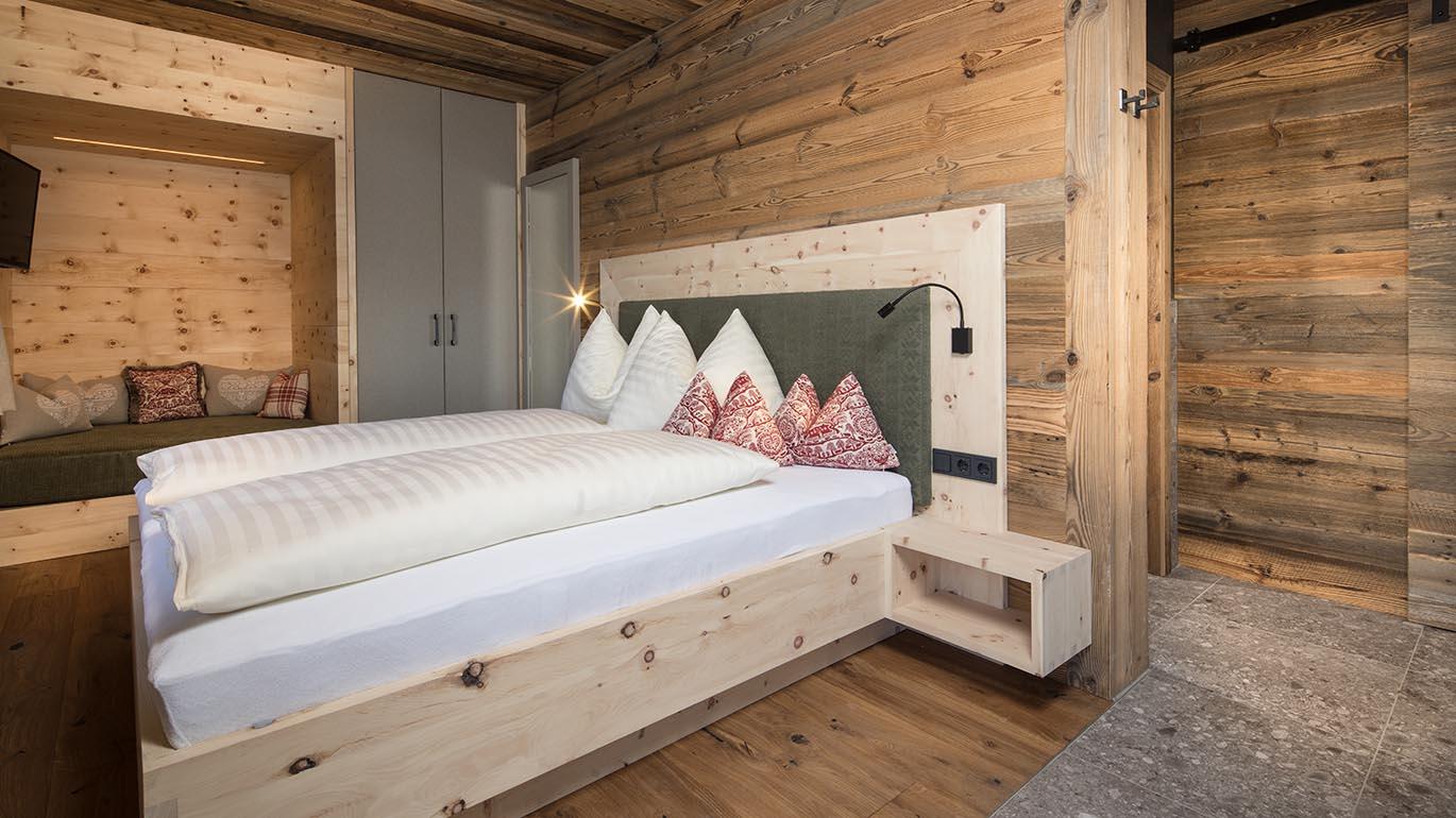 A cozy bedroom with a large double bed and wooden paneling. The warm tones and stylish design create an inviting atmosphere.