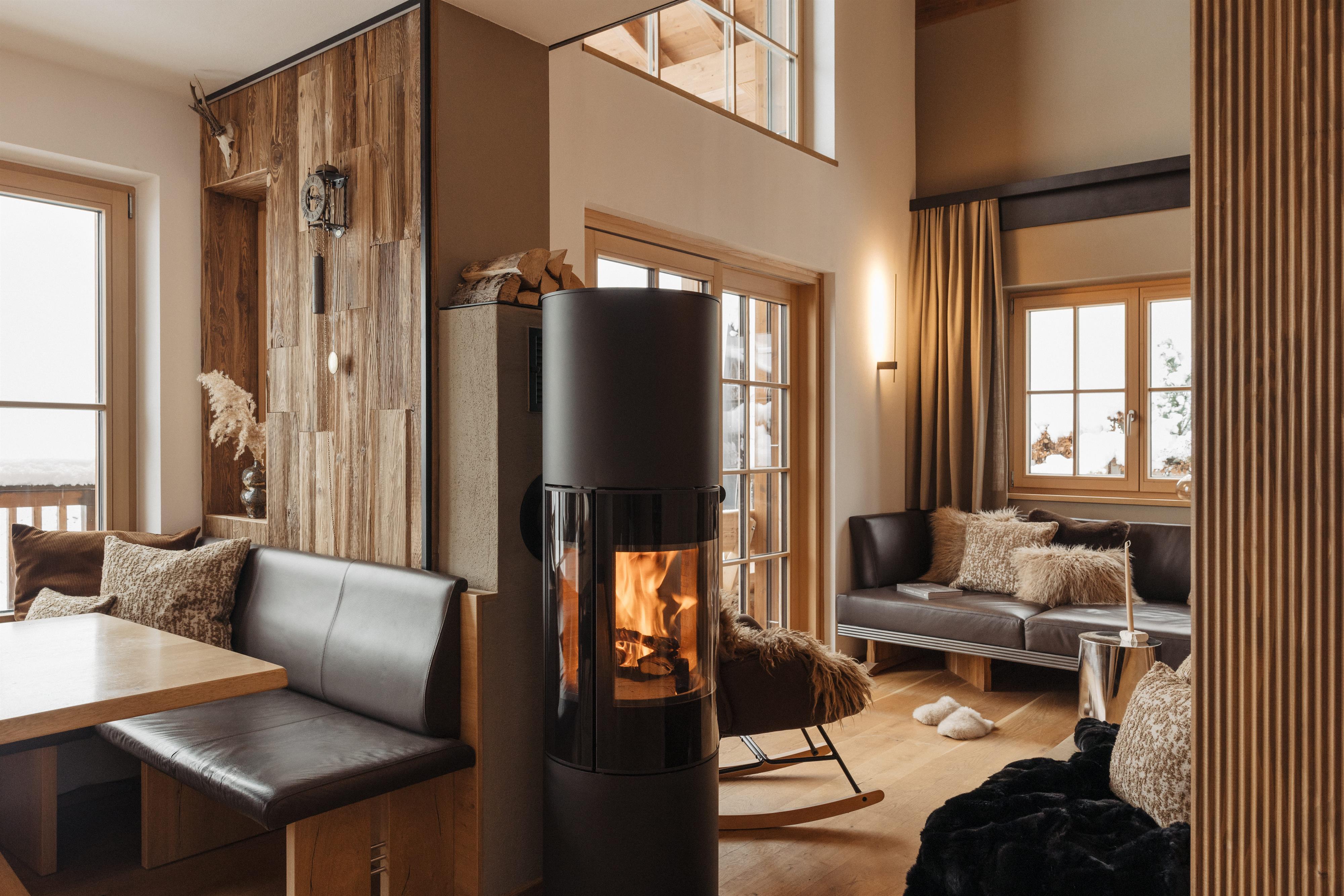 A cozy living space with wood walls and large windows. A modern stove provides warmth and an inviting atmosphere.