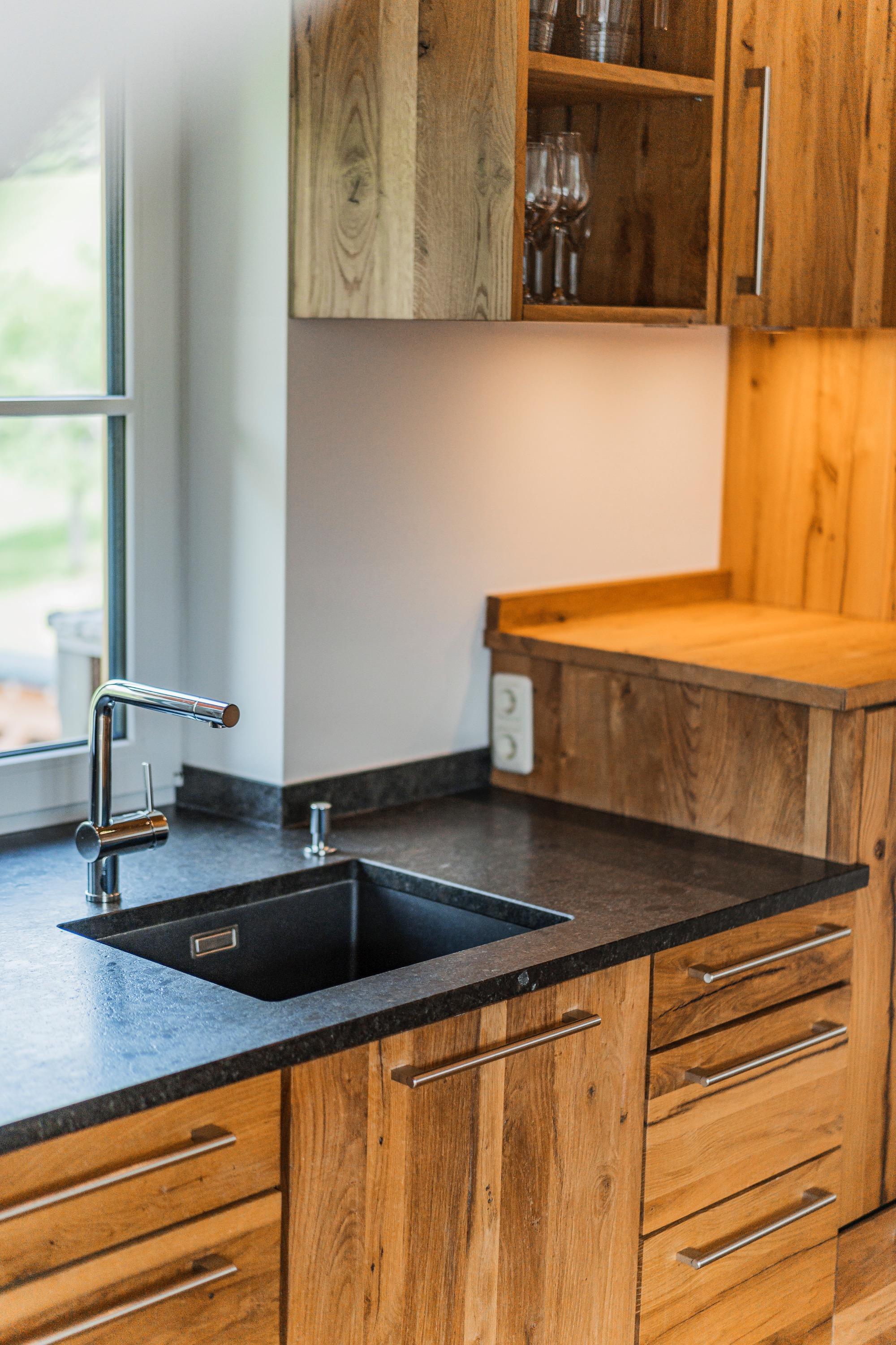 A modern kitchen with wooden cabinets and an elegant countertop. The sink area is equipped with a modern faucet.