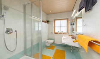 A modern bathroom with a shower and bright colors. The combination of white tiles and colorful towels creates an inviting atmosphere.