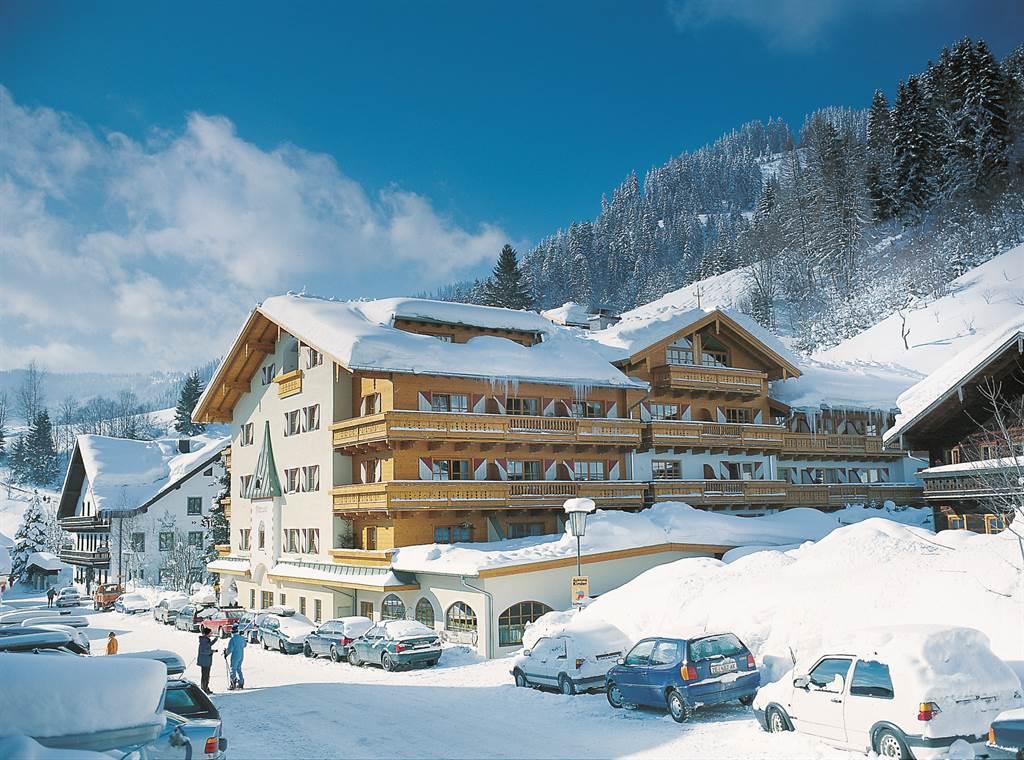 A beautiful mountain hotel in the snow with snow-covered roofs. The surroundings are wintry and picturesque, perfect for a skiing holiday.