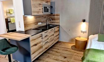 A modern kitchenette with wooden fronts and a small seating area. The space feels bright and inviting.