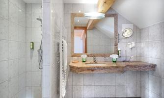 A modern bathroom with a bright tiled floor and an elegant stone countertop. It includes a shower and a large mirror.