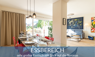 A modern dining area with a large table and colorful chairs. It offers a beautiful view of the terrace and is bright and inviting.