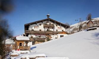 A cozy house in a winter landscape. It is surrounded by snow and has balconies with appealing decoration.