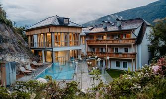 A cozy hotel with a pool and large windows. In the background, mountains and a picturesque landscape can be seen.