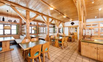 A cozy interior with wooden furniture and a warm ambiance. Large windows let in plenty of light and create an inviting atmosphere.
