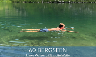 A boy swims in a clear, green mountain lake. Surrounded by a picturesque landscape with green hills.