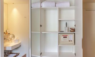 A modern cabinet with open shelves and fresh towels. In the background, a bathroom with a sink is visible.