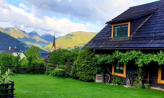 A cozy house with a well-kept garden. In the background, snow-covered mountains can be seen.