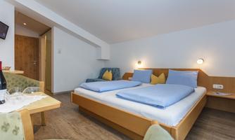 A modern bedroom with two beds and light pillows. The room has wooden details and a cozy atmosphere.
